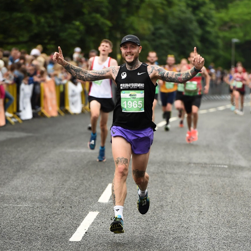 Oly Newton running the Ilkley 2021 race in his Run4YourMind singlet, arms raised